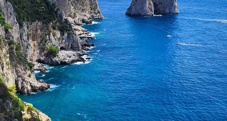 Brilliant blue sea laps rugged limestone cliffs and rock stacks off Capri’s coast.