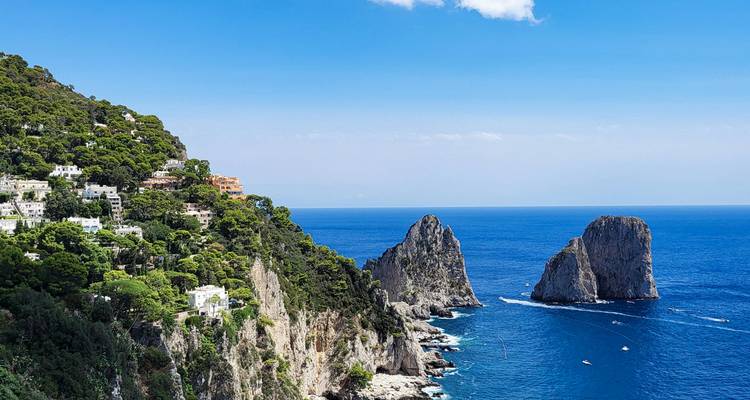 Kristalhelder zee en de iconische Faraglioni-rotsformaties gezien vanaf Capri's weelderige kliffen.