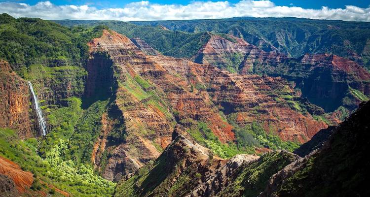 Le vaste canyon de Waimea avec ses falaises aux couches rouges et vertes, ses ravins profonds et sa haute cascade.