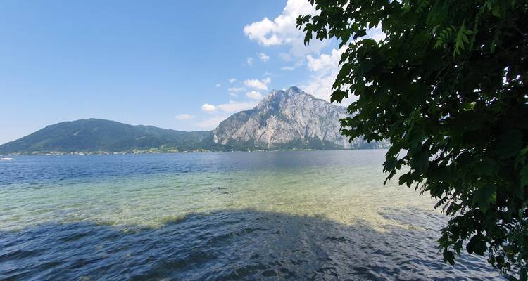 Lac alpin d'un bleu cristallin avec une eau turquoise peu profonde au premier plan et un pic imposant en arrière-plan.