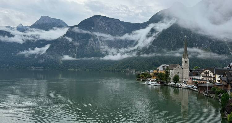 Vue classique de la carte postale du village de Hallstatt avec le clocher de l'église, les maisons au bord du lac et les nuages bas.