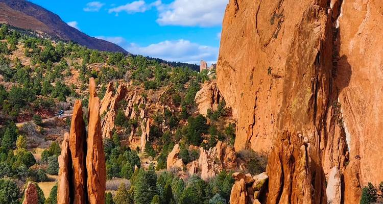 Towering orange rock formations frame a lush valley of pines in Garden of the Gods park.