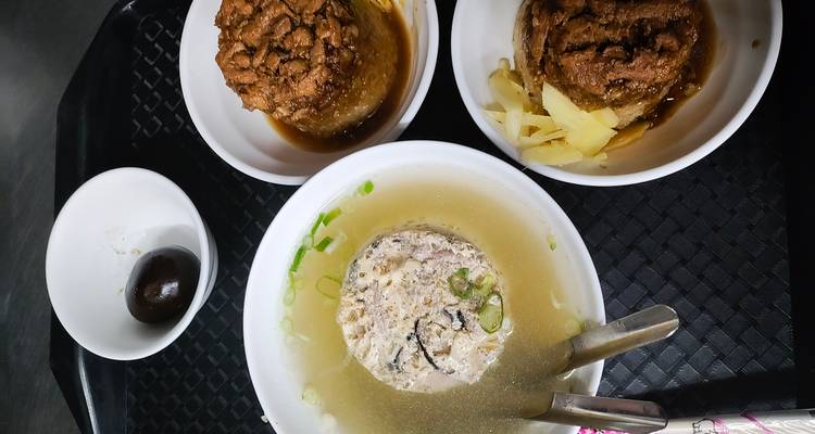 Platos tradicionales taiwaneses incluyendo sopa, pasteles de arroz con carne y huevos de té en una bandeja.