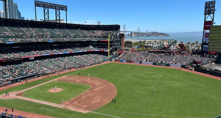 Aerial view of a baseball game in progress at Oracle Park with Bay Bridge in background