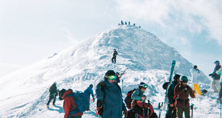 Les skieurs se rassemblent au sommet enneigé avec leur équipement, se préparant à descendre la montagne.