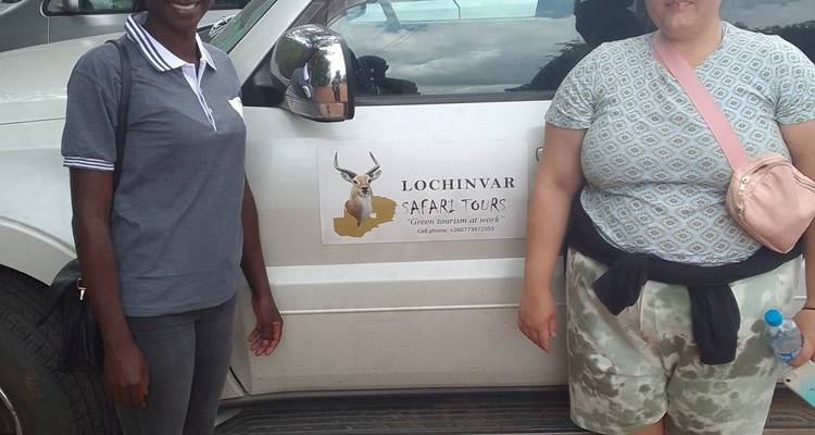Deux voyageurs se tenant à côté d'un véhicule portant l'étiquette Lochinvar Safari Tours.