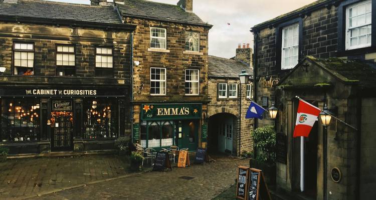 Atmospheric stone courtyard with warmly lit shops and flags in Haworth.