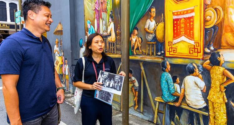 A tour guide explains a colorful street mural to a visitor during a walking tour.