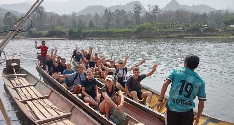 Un grand groupe de voyageurs dans des pirogues acclame tandis qu'il navigue sur un large fleuve tropical.
