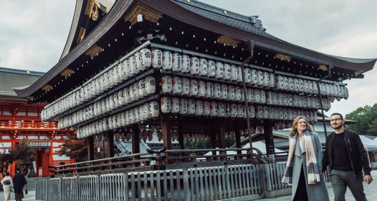 Ein Paar spaziert in sanftem Abendlicht an Reihen von Laternen am Yasaka-Schrein in Kyoto vorbei.