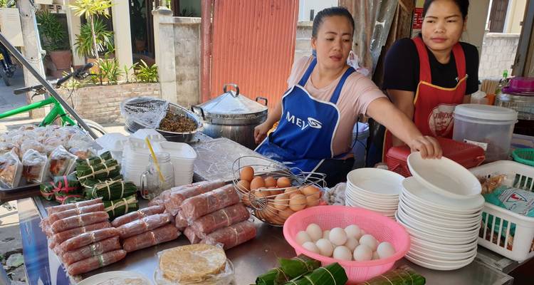 Street food vendors arrange eggs, sausages and snacks at a bustling outdoor stall.