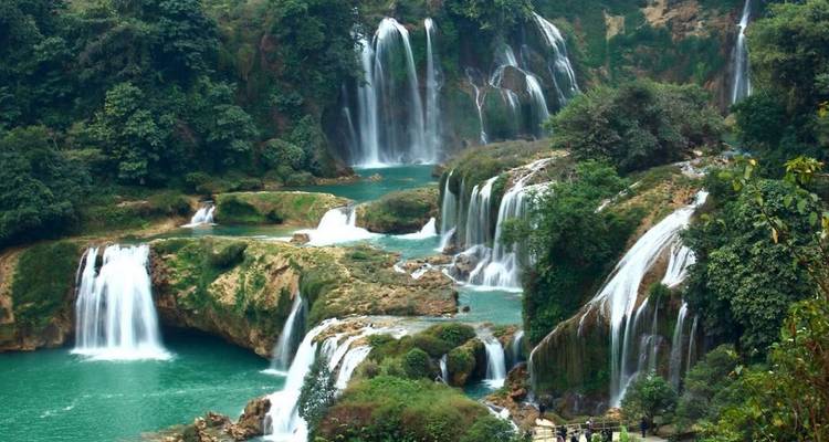 Serie de cascadas color turquesa que se deslizan sobre acantilados cubiertos de densa selva hacia piscinas color esmeralda.