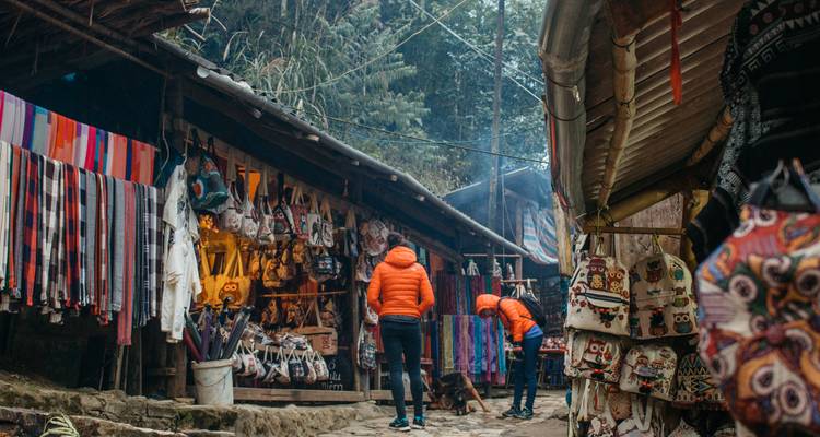 Colourful textile stalls and handicraft shops line a narrow market alley in the misty hills of Sapa.