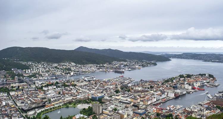 Amplio panorama aéreo de la ciudad de Bergen, el puerto y los fiordos circundantes bajo un cielo nublado