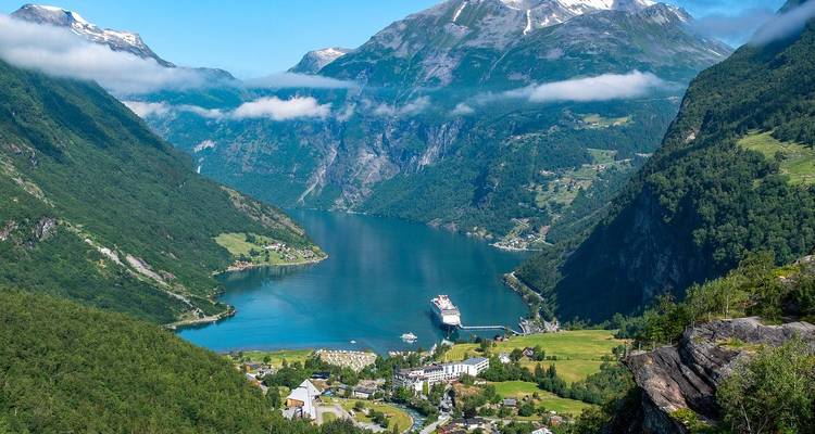Vista elevada del Fiordo de Geirangerfjord con crucero, pueblo y montañas exuberantes