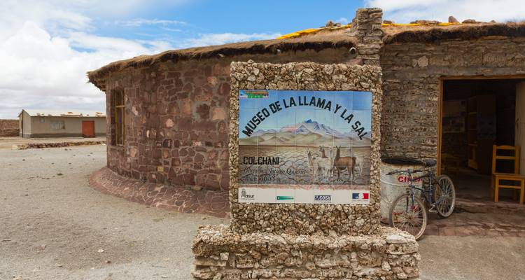 Stone and thatch building with sign for Museo de la Llama y la Sal in Colchani village