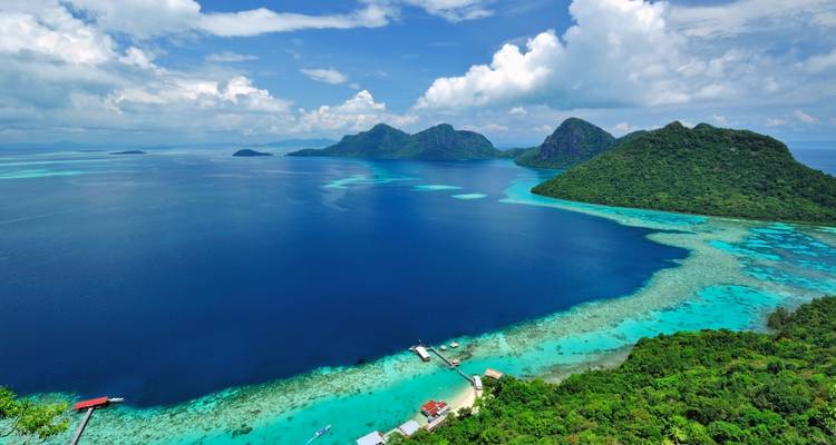 Vue aérienne de lacs turquoise et d'îles verdoyantes entourées par une mer bleu profond.