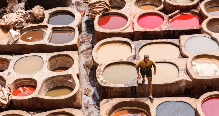Worker walks among vibrant dye pits at the famous Fes leather tannery.