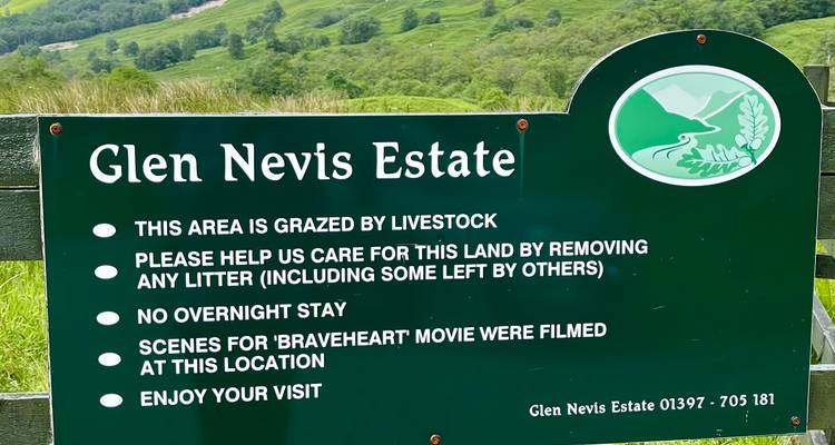 Panneau informatif du Glen Nevis Estate se dressant sur fond de collines verdoyantes ondoyantes.
