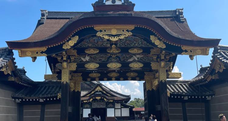 Ornate Karamon gate of Nijo Castle with gold leaf carvings gleaming under blue skies.
