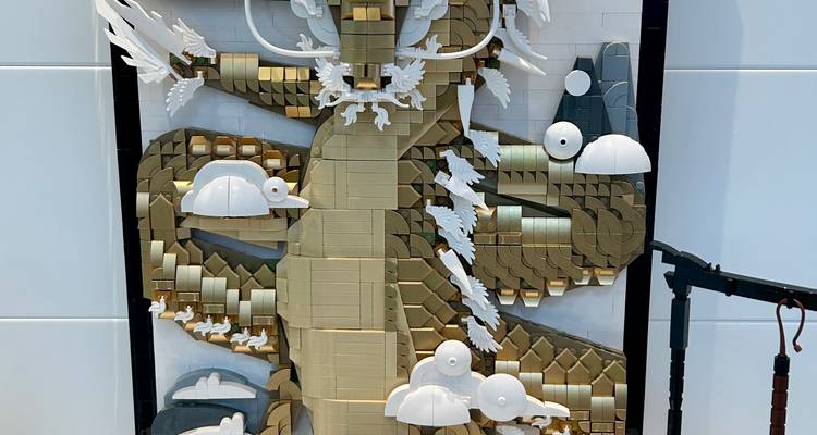 Gouden en witte LEGO muurschildering met een prachtige draak tegen een lichte achtergrond.