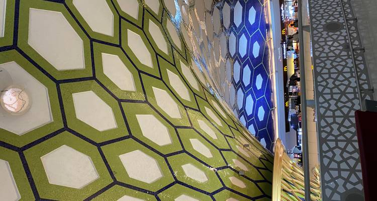 Colorful mosaic honeycomb ceiling of Abu Dhabi airport terminal with shops below