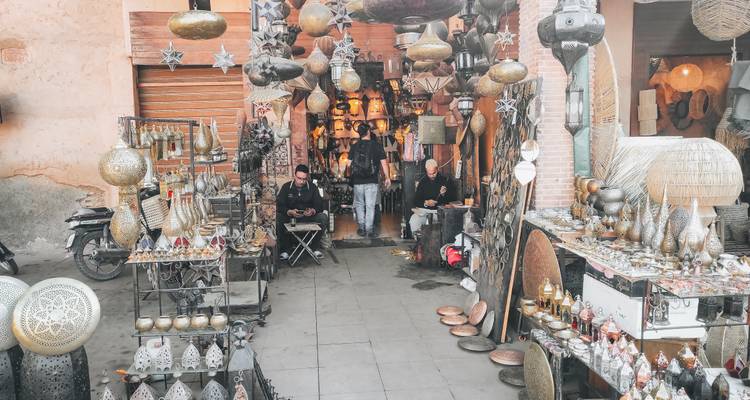 Boutique de lanternes et de travail du métal dans un souk avec des artisans travaillant parmi des lampes ornées.