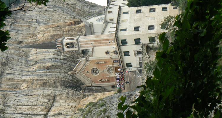 Eine dramatische Schutzkirche, die in eine senkrechte Felswand gebaut wurde, zieht Besucher auf einer schmalen Terrasse an.