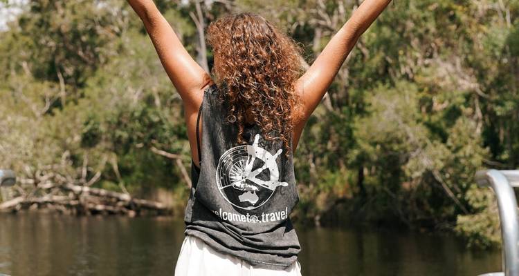 Voyageur joyeux levant les bras lors d'une excursion en bateau à travers les cours d'eau luxuriants de la forêt tropicale australienne.