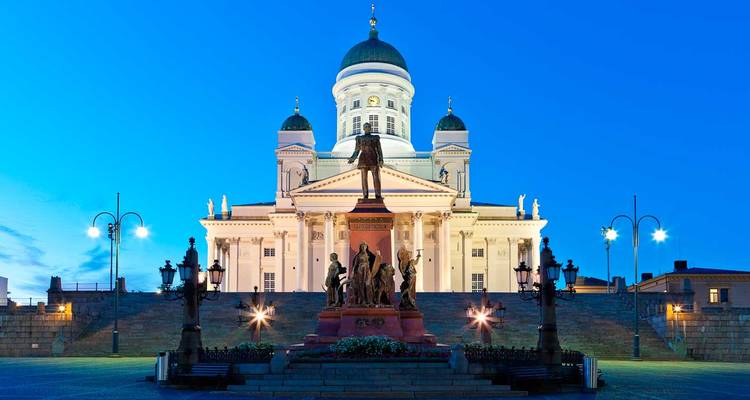 Symmetrisch nachtelijk uitzicht van de Helsinkische Kathedraal verlicht tegen een diepblauwe hemel.