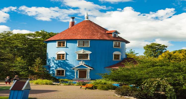 Grillig blauw rond torenhuisje uit Moominworld omringd door bomen en bezoekers.