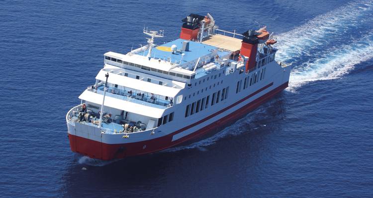 Luchtfoto van een rood-wit passagiersveer die door diepblauw zeewater snijdt en een kielzog achterlaat.