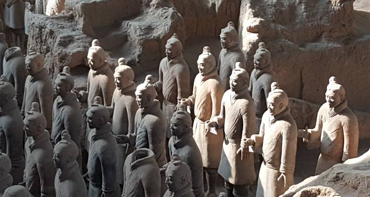 Rijen Terracotta Warriors die in hun uitgravingsput staan, zacht verlicht door natuurlijk licht.