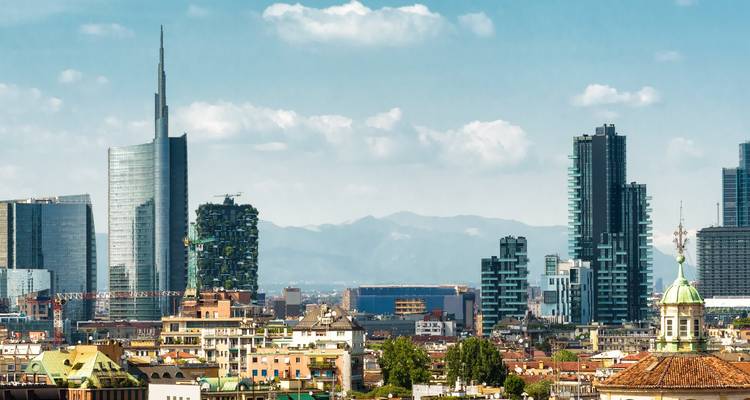 Skyline de la moderna Milán con rascacielos de vidrio elevándose detrás de los tejados clásicos y los Alpes a lo lejos.