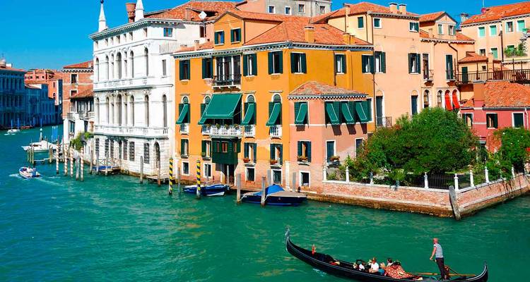 Gondolier, der Fahrgäste entlang eines smaragdgrünen Kanals neben farbenfrohen Palästen steuert.