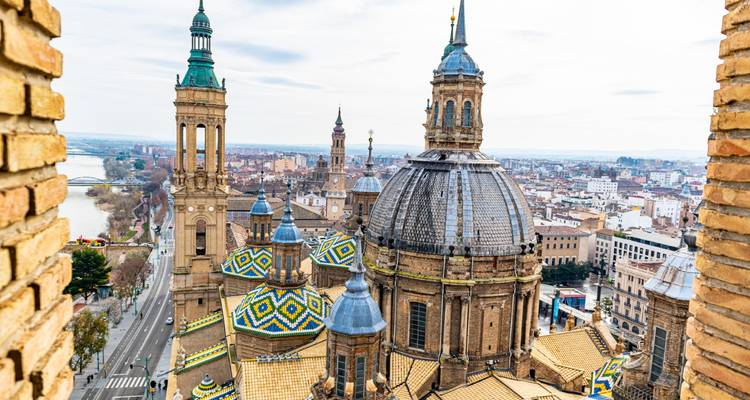 Vista privilegiada de la Basílica del Pilar de Zaragoza con sus cúpulas estampadas y el paisaje urbano junto al río Ebro.