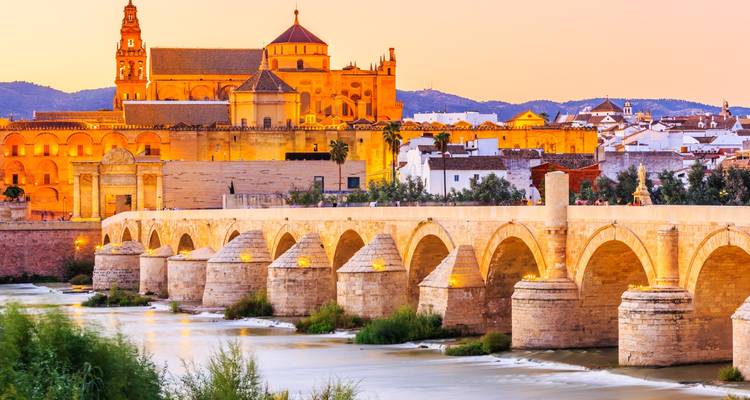 Le Pont romain doré et la Mezquita-Cathédrale se reflétant dans le fleuve Guadalquivir au crépuscule à Córdoba.