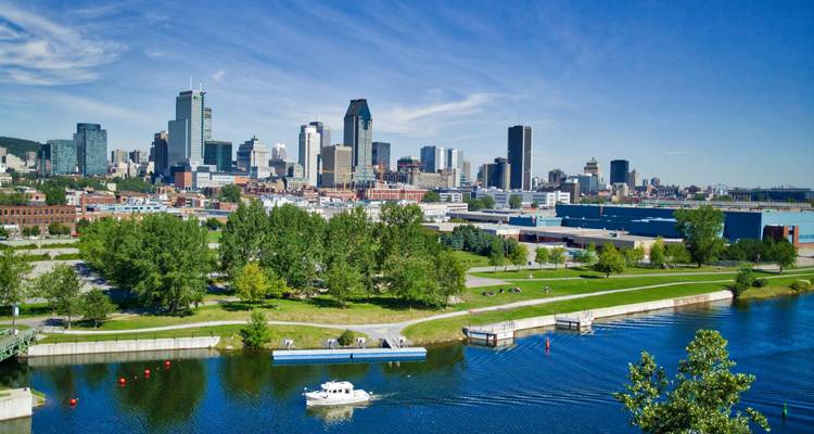 Montreal skyline viewed across the St. Lawrence River with boat and green park