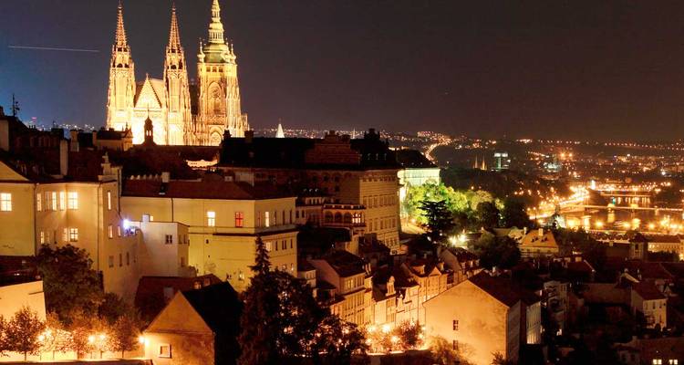 Nächtliches Panorama der Prager Burg und des beleuchteten St.-Veits-Doms über den Lichtern der Stadt.