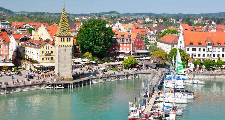 Hafenfront-Szenerie in Lindau am Bodensee mit dem Mangturm-Turm, Yachthafen und Cafés entlang der Promenade.