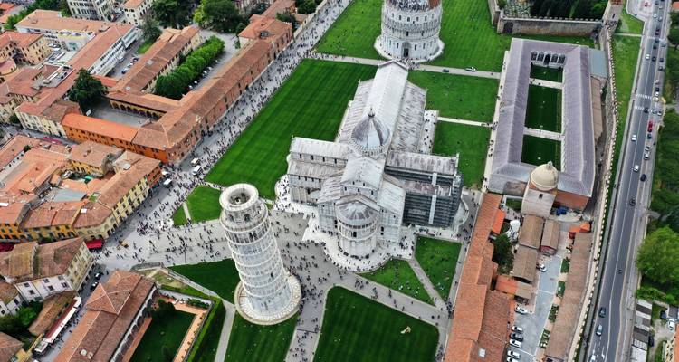 Drone view over Pisa’s Leaning Tower and cathedral complex with crowds and geometric lawns.