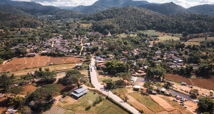 Vue aérienne d'une petite ville de vallée rurale entourée de collines boisées et de terres agricoles dans le nord de la Thaïlande