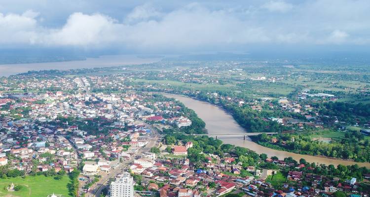 Panorama aérien de la ville de Paksé s'étendant le long du Mékong sous des nuages bas