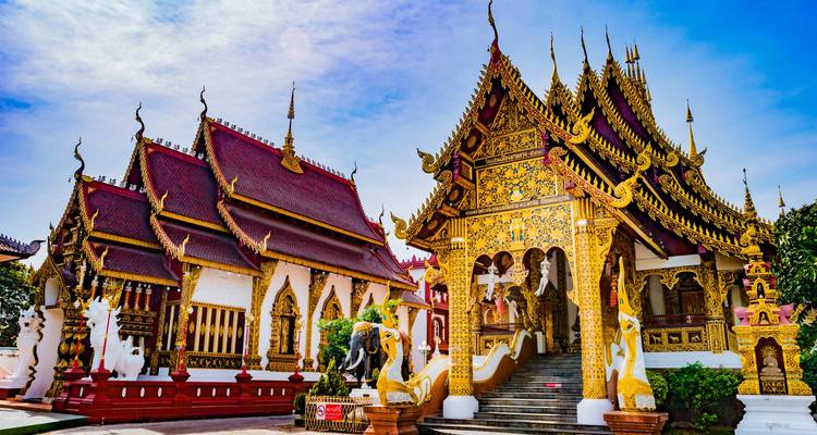 Fachada elaborada del templo dorado con escaleras de naga y salones con techos rojos en Chiang Mai.