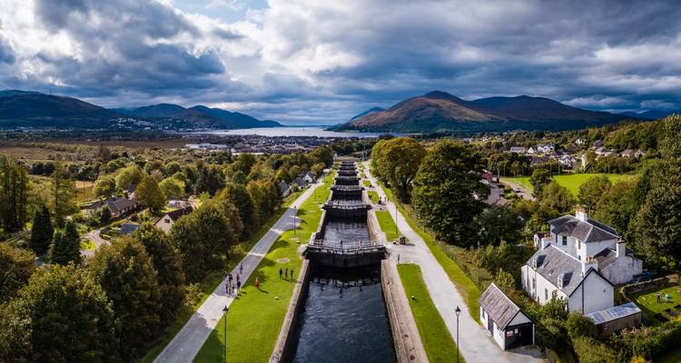 Vue aérienne des écluses de Neptune's Staircase du canal Calédonien s'étendant vers des lochs et des montagnes lointains.
