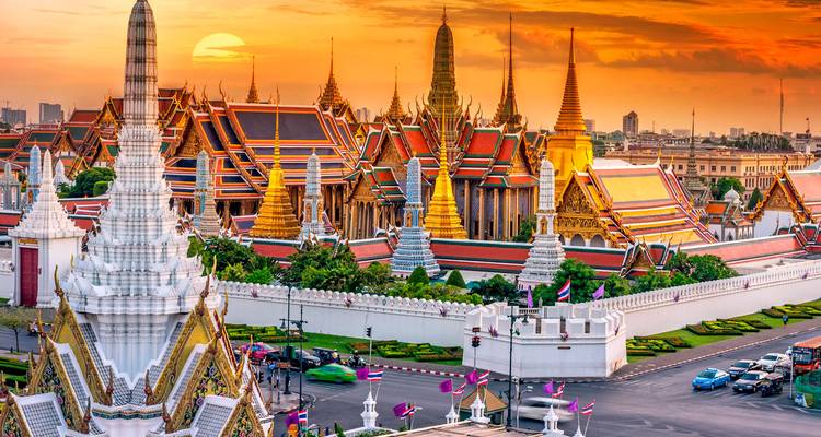 Coucher de soleil spectaculaire sur le complexe du Temple du Bouddha d'Émeraude de Bangkok avec des toits et des flèches vibrants qui brillent.