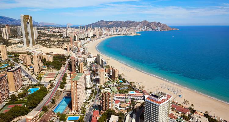 Luftaufnahme der Skyline von Benidorm, die einen weitläufigen Sandstrand und das türkisfarbene Meer säumt.