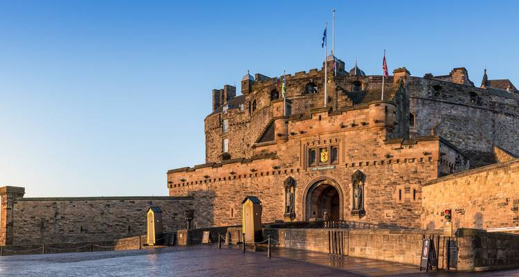 Stenen gevel en ingang van Edinburgh Castle die gloeit in het warme ochtendlicht.