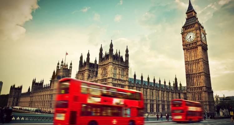 Iconische Big Ben en het Parlementsgebouw met twee rode dubbeldekkers in bewegingsonscherpte bij schemering.