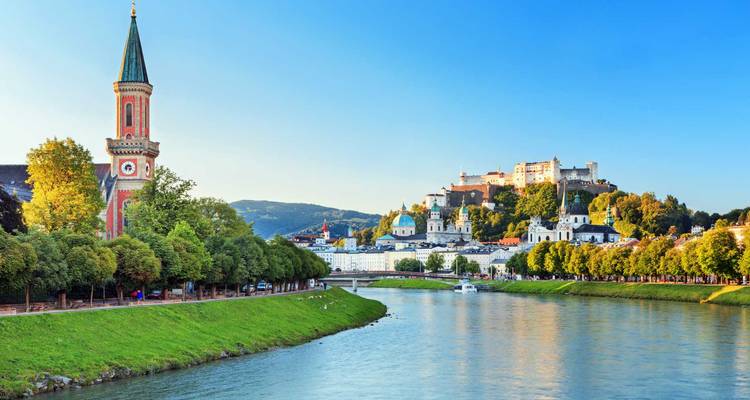 Klare Aussicht entlang der Salzach auf die Altstadt von Salzburg und die Festung unter blauem Himmel.